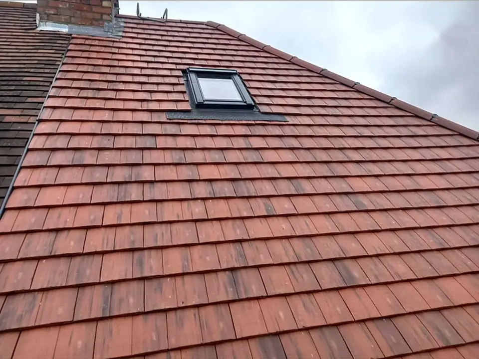 Close-up of a clay plain tile re-roof around a Velux roof window